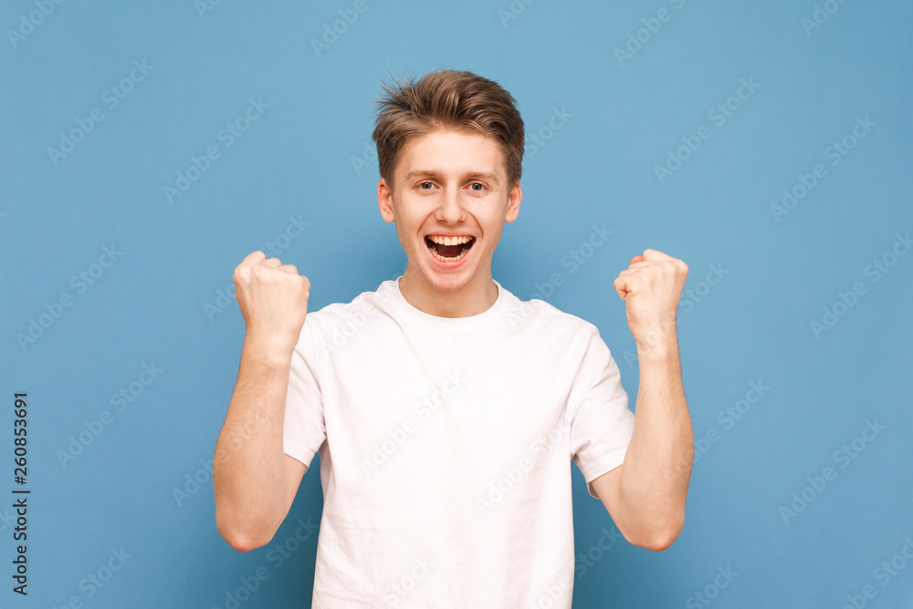 Portrait of a joyful guy with his hands raised on a bullish background, wearing a white T-shirt. Happy young man rejoices, looks at the camera and smiles. Isolated. Portrait of a joyful guy with his hands raised on a bullish background, wearing a white T-shirt. Happy young man rejoices, looks at the camera and smiles. Isolated.