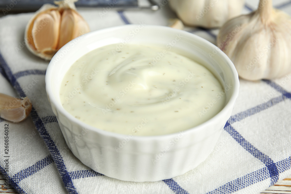 Composition with bowl of garlic sauce on plaid fabric Composition with bowl of garlic sauce on plaid fabric