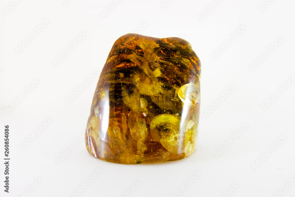 Multi-colored amber stone with yellow and red parts with the tree bark on the inside. Amber for jewelry. Precious stones. Multi-colored amber stone with yellow and red parts with the tree bark on the inside. Amber for jewelry. Precious stones.