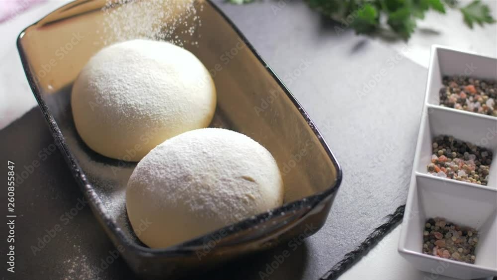 Sprinkling flour over fresh dough for pizza or bread Sprinkling flour over fresh dough for pizza or bread