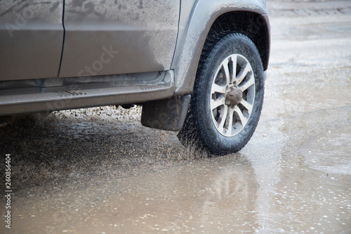 Moving car sprays puddle when heavy rain drops on concrete. © Александр Поташев