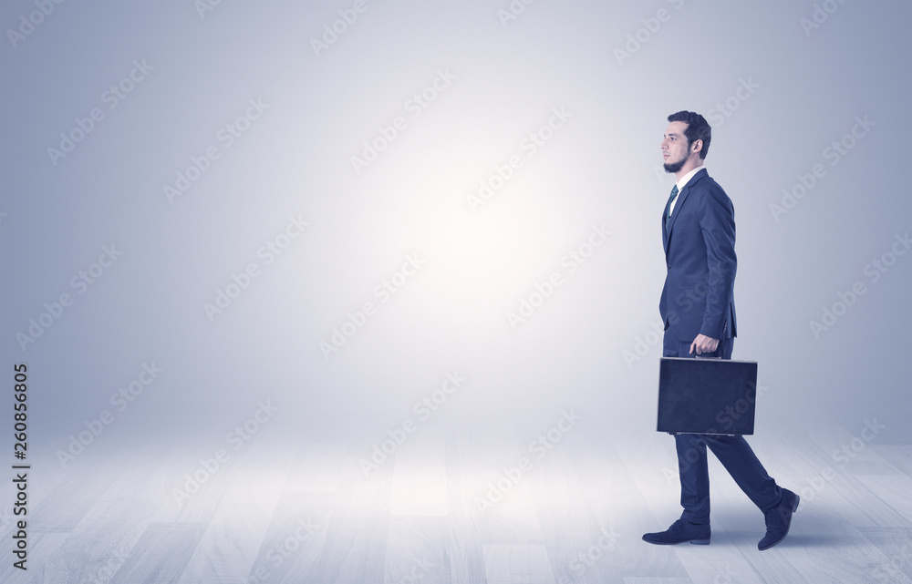 Successful businessman walking in front of an empty wall with briefcase on his hand
Successful businessman walking in front of an empty wall with briefcase on his hand