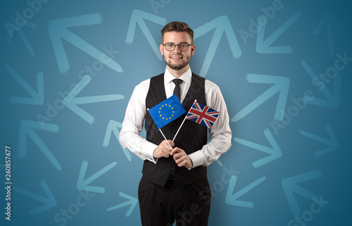 Cheerful elegant boy standing with flag on his hand and chalk drawn arrows around