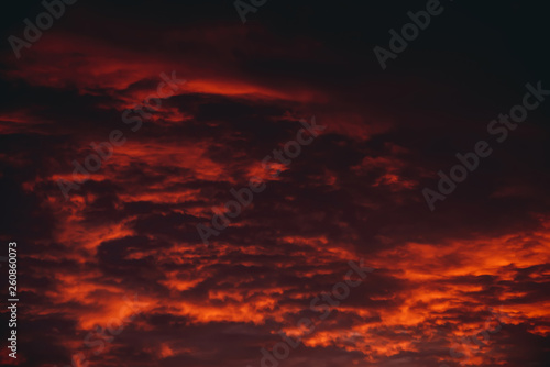 Fiery red blood vampire dawn. Amazing warm dramatic fire cloudy sky. Vivid orange sunlight. Atmospheric background of sunrise in overcast weather. Hard cloudiness. Storm clouds warning. Copy space. © Daniil