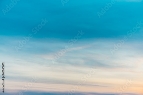 Sunset sky with orange yellow light clouds. Colorful smooth blue sky gradient. Natural background of sunrise. Amazing heaven at morning. Slightly cloudy evening atmosphere. Wonderful weather on dawn.