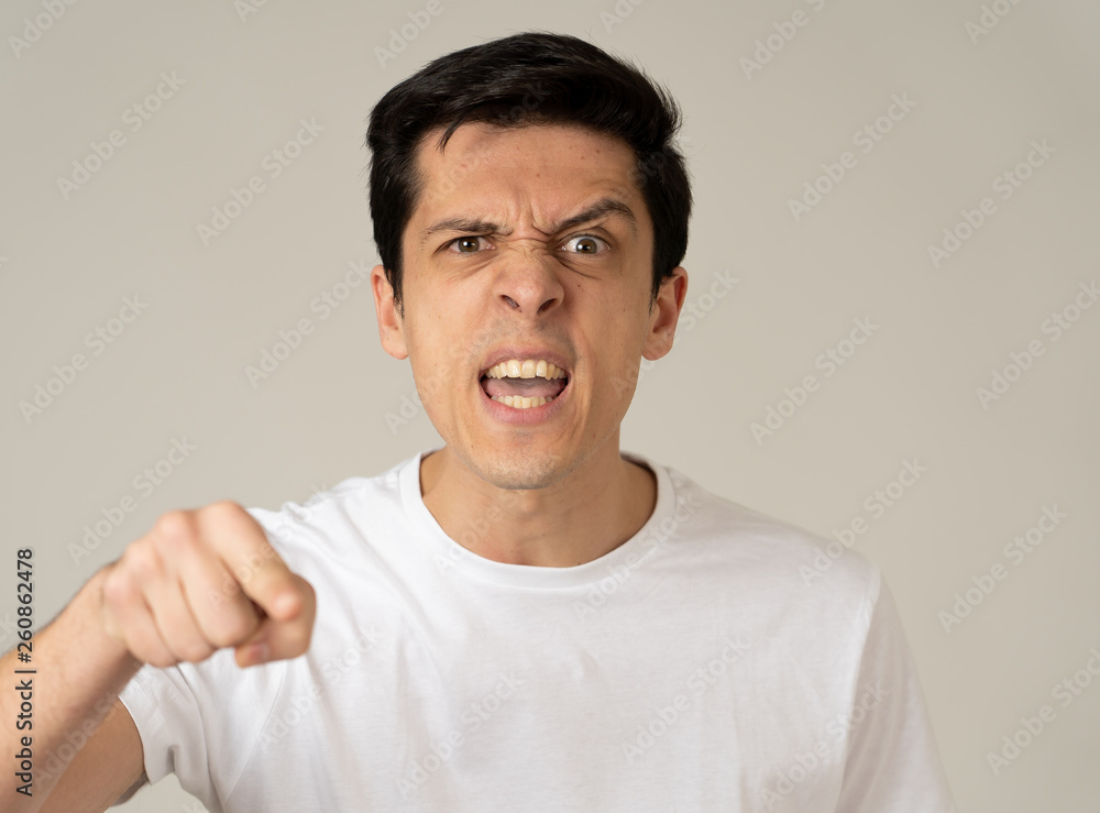 Portrait of a beautiful young man with angry face looking furious. Human expressions and emotions Portrait of a beautiful young man with angry face looking furious. Human expressions and emotions