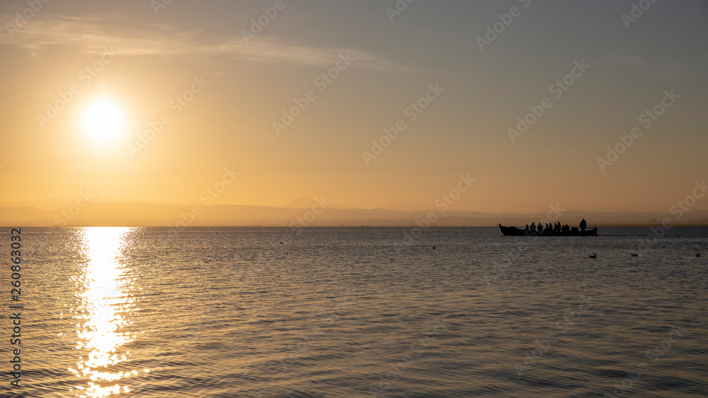 Boat with people in Albufera of Valencia at sunset.