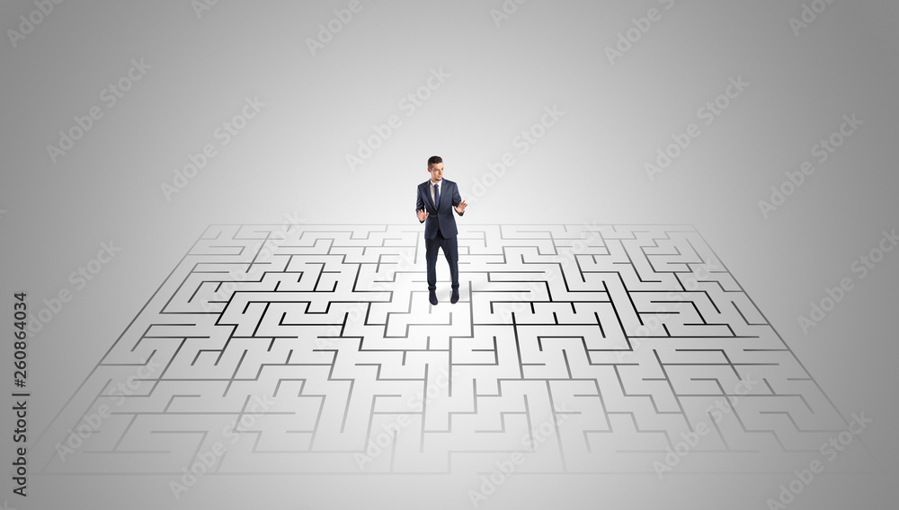 Elegant businessman looking for a solution in a middle of a maze
Elegant businessman looking for a solution in a middle of a maze