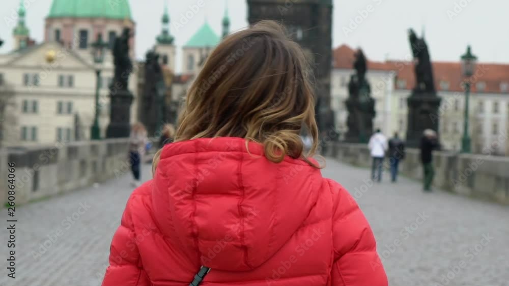 Girl walking at the bridge in European city and looking at the cityscape Girl walking at the bridge in European city and looking at the cityscape
