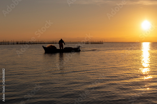 Man fishing in a boat at sunset in Albufera of Valencia.