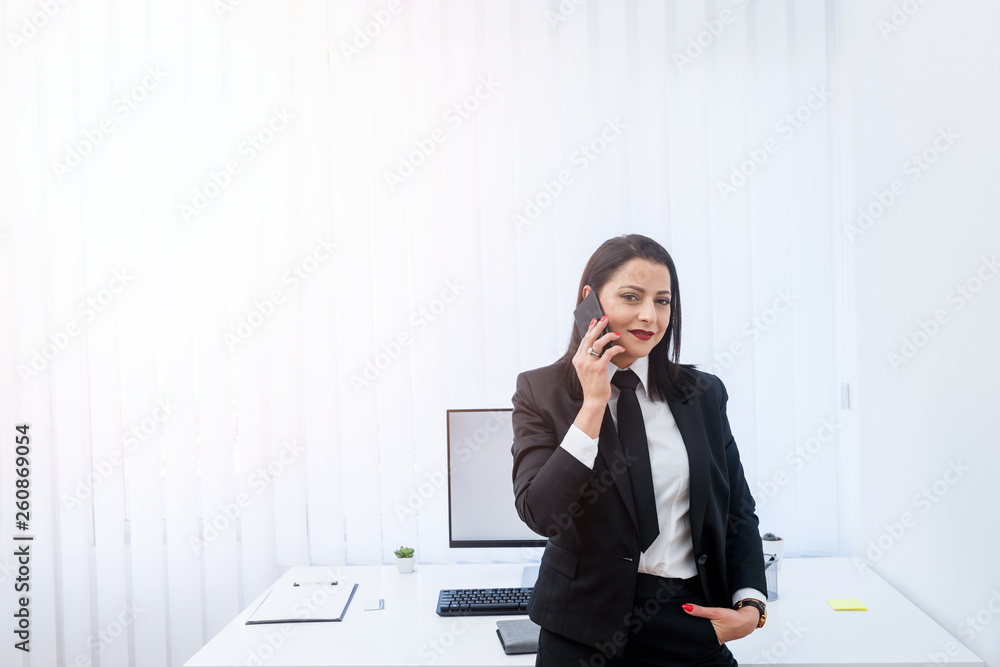 Beautiful business woman standing in the office and talking on the phone. Beautiful business woman standing in the office and talking on the phone.