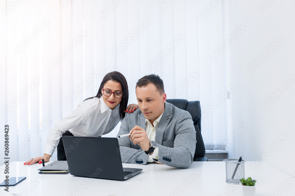 Two successful young people checking informations on the laptop while being in the modern office. Two successful young people checking informations on the laptop while being in the modern office.