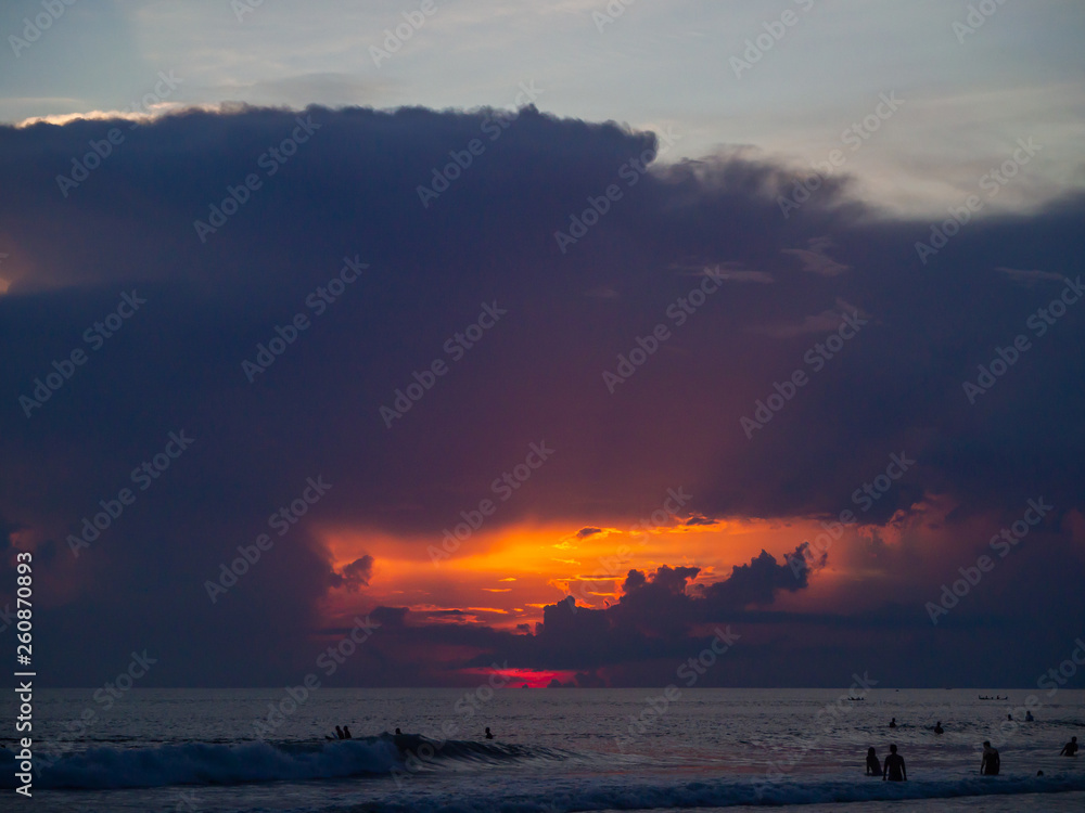 Surfers on the background of beautiful sunset clouds. Bali.