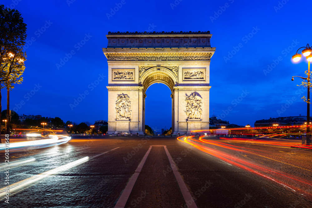 Paris street at night with the Arc de Triomphe in Paris, France.