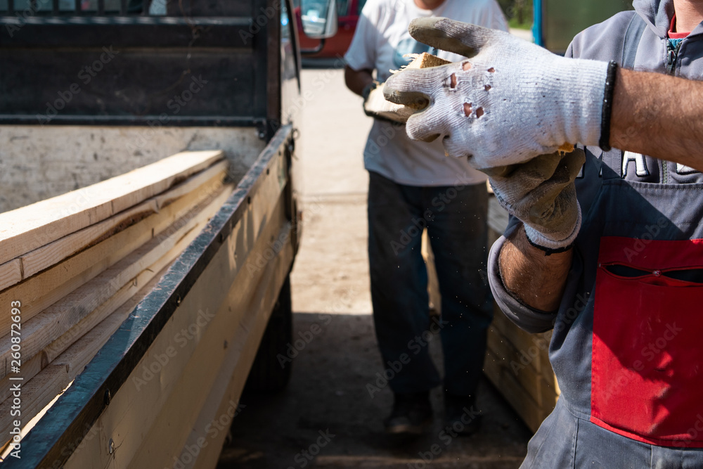 Construction workers holding loading material planks by the truck ready to delivery to the construction site Construction workers holding loading material planks by the truck ready to delivery to the construction site