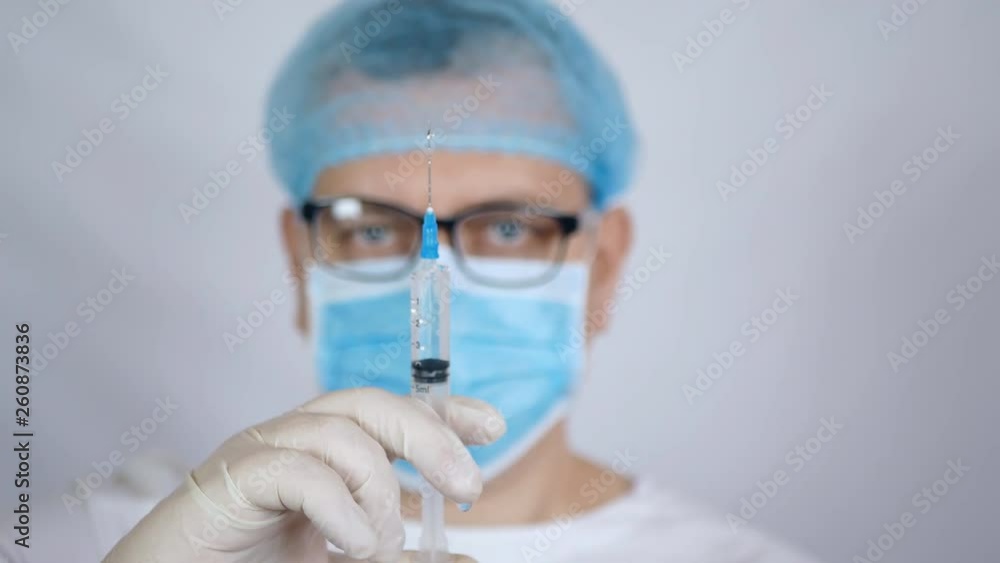 Doctor holding a big syringe with a clear liquid, focus on the syringe. Prepare a syringe for injection.Close-up. Doctor holding a big syringe with a clear liquid, focus on the syringe. Prepare a syringe for injection.Close-up.