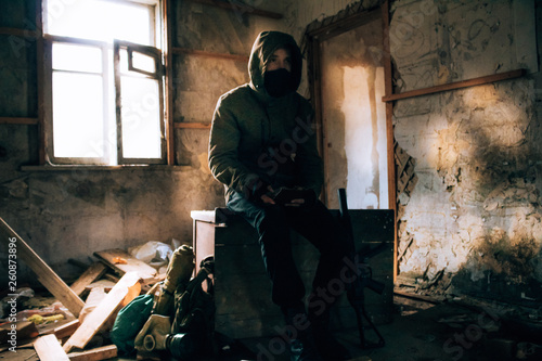 Stalker, a soldier guy in uniform and with a gun sits in an old, abandoned house