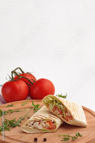 Shawarma in pita and natural organic tomatoes with greens, on a wooden background