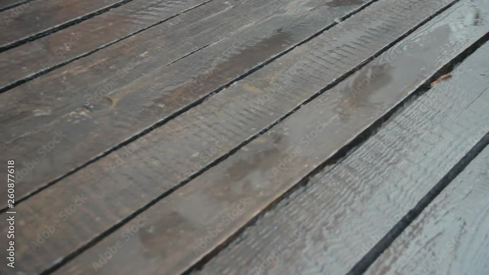 Old unpainted boards in the rain. The camera is moving. Raindrops crashing on wood flooring. April rain. Close-up. Nostalgic mood Old unpainted boards in the rain. The camera is moving. Raindrops crashing on wood flooring. April rain. Close-up. Nostalgic mood