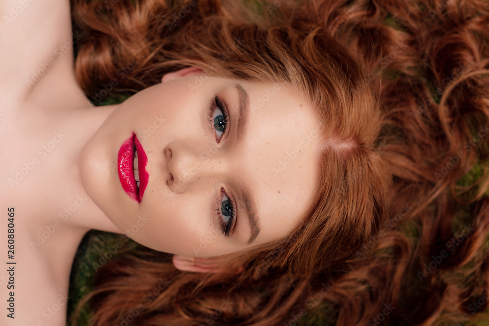 top view of beautiful young redhead woman with red lips looking at camera top view of beautiful young redhead woman with red lips looking at camera