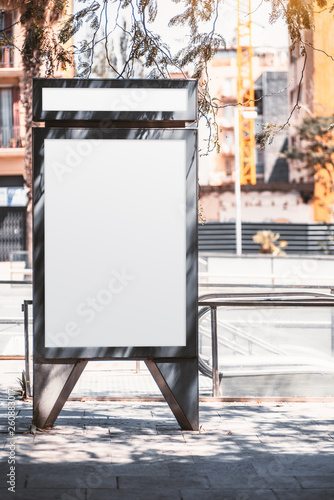 Photography A vertical empty poster mock-up in the shadow of trees; white advertising billbo
