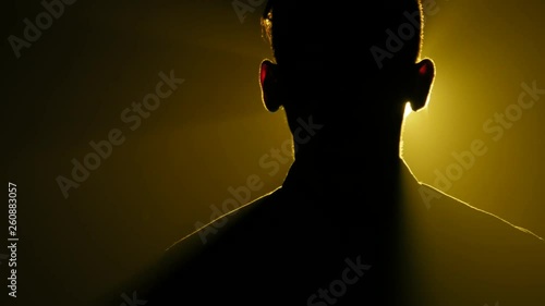 silhouette of young man standing in the dark smoky room with yellow light
