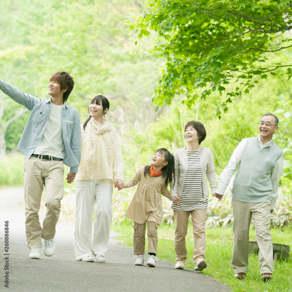 Obraz premium 新緑の中で手をつなぐ3世代家族
