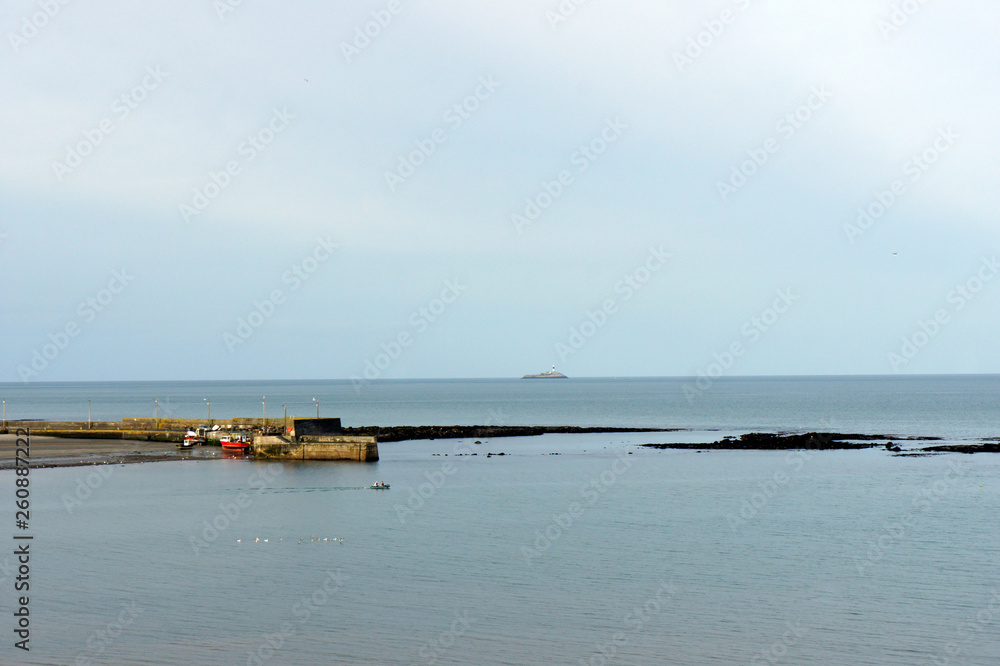 Seascape. Small fishing port and lighthouse on the horizon.