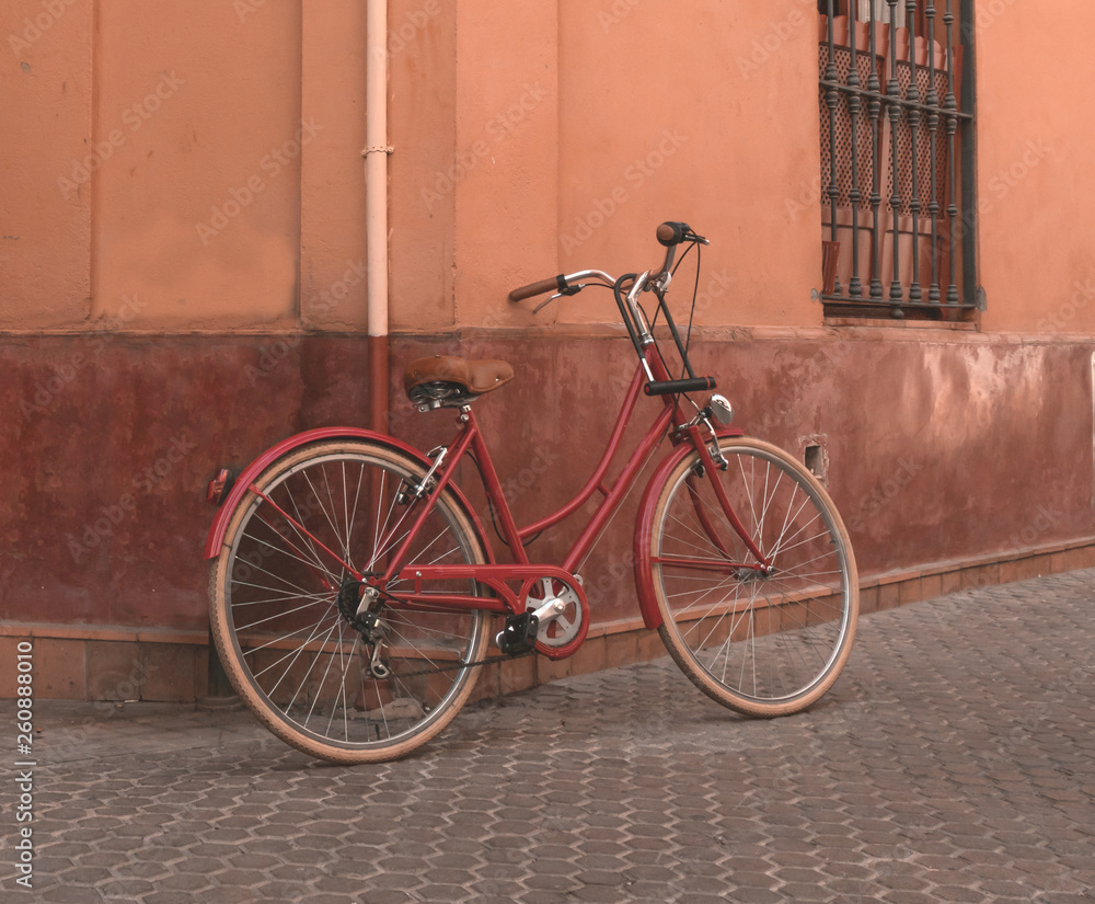 Red bicycle resting on the wall