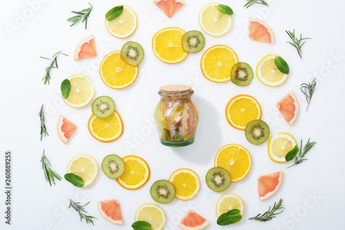 flat lay with fresh sliced kiwi, oranges, lemons, grapefruits, mint, rosemary and detox drink in jar
