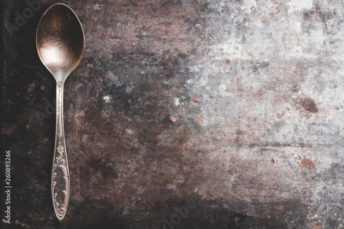 Old metal spoon on the rustic background. Selective focus.