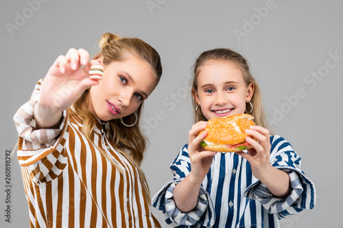 Cheerful young girls holding big burger in both hands