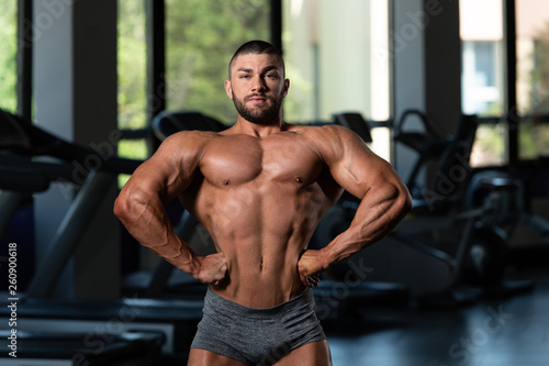 Fototapeta Naklejka Na Ścianę i Meble -  Handsome Muscular Man Flexing Muscles In Gym