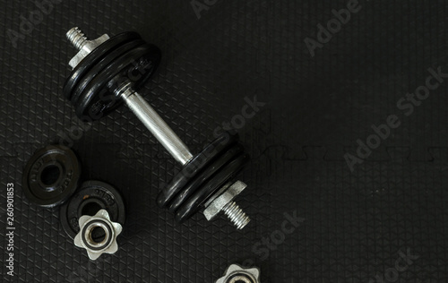 Top view of Iron dumbbells or weights on black floor with copy space for text. Flat lay composition. Health care concept.