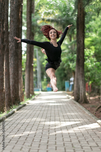 Happy redhead smiling girl dancing in a green park on Brazil in a summer day