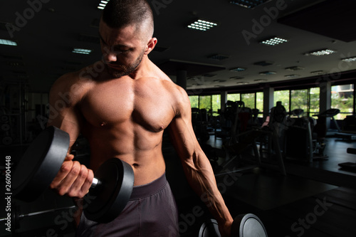 Bodybuilder Exercising Biceps With Dumbbells