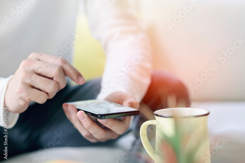 Cropped shot of man using smartphone while relaxing at home.