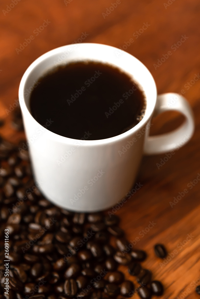Fototapeta premium Black coffee in white cups by hand on wooden floors and coffee beans