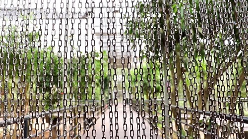 A line of steel chain protects entry to the aviary with tropical plants and exotics birds. photo