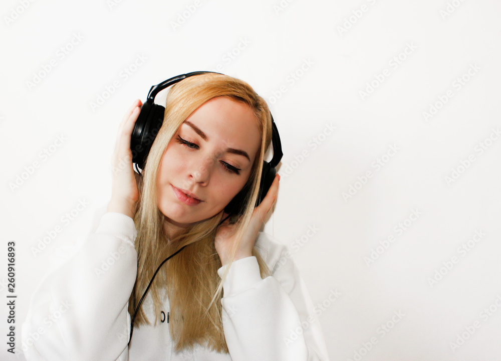 Close-up portrait of happy young woman with blonde hair listening music . Smiling Woman with in headphones listening to music on white background , top view. Attractive funny model. Copy Space. Close-up portrait of happy young woman with blonde hair listening music . Smiling Woman with in headphones listening to music on white background , top view. Attractive funny model. Copy Space.