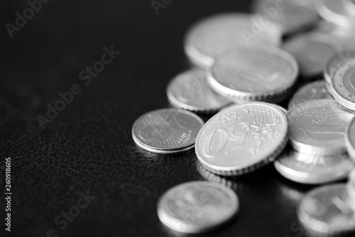 Euro coins scattered on a dark background close up. Black and white