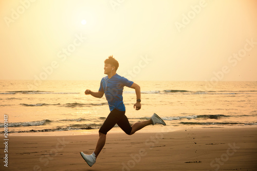 young Man running on beach at sunset