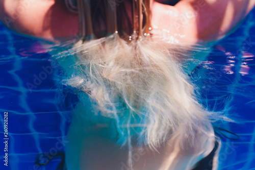 Beautiful woman raising her head out of the water in a swimming pool.