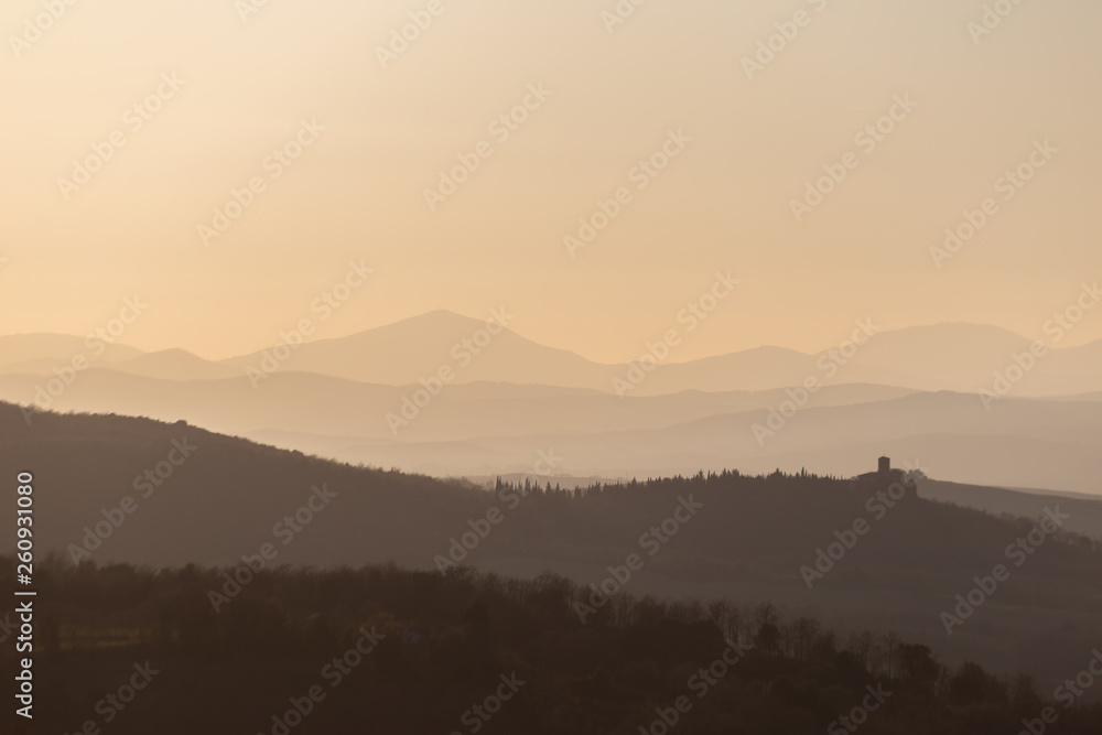Fototapeta premium Beautiful view of Tuscany hills at sunset, with mist and warm colors