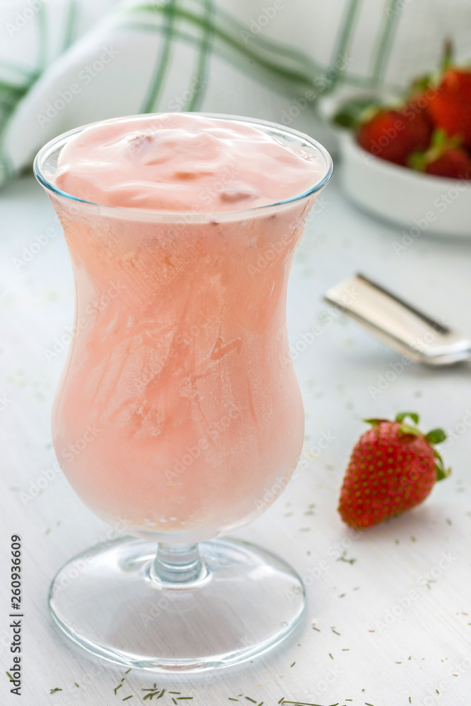 Pink strawberry mousse in goblet glass on white wooden background with text space. Pink strawberry mousse in goblet glass on white wooden background with text space.