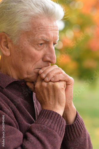 Close up portrait of thoughtful senior man in autumn park