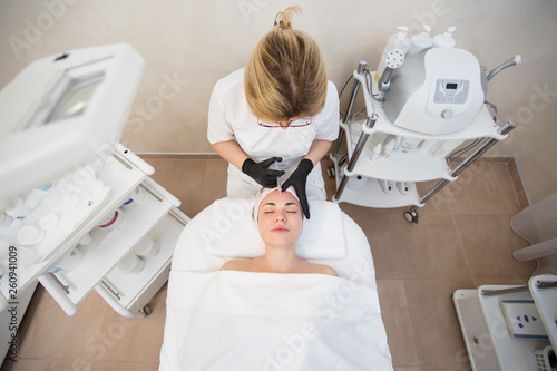 Beautician making injection in woman's face, close-up. Biorevitalization procedure. Injection cosmetology. Close-up of hands in gloves holding syringe. The view from the top