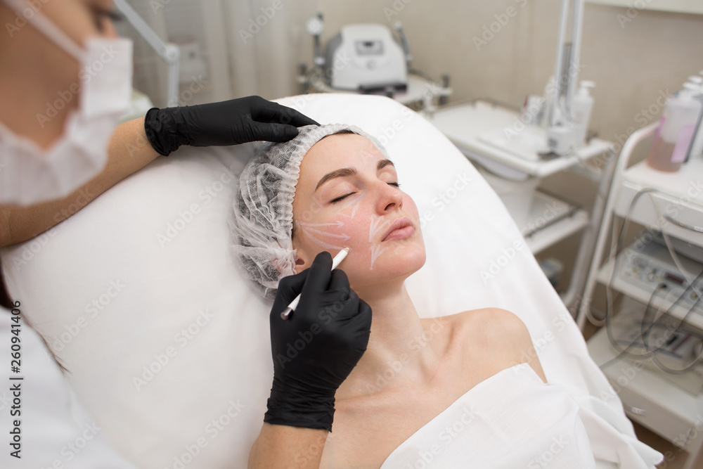 Beautician draws the contours of a white pencil on the face of the patient. Schematic marking before contouring. Close-up preparation of the face for cosmetic plastic surgery Beautician draws the contours of a white pencil on the face of the patient. Schematic marking before contouring. Close-up preparation of the face for cosmetic plastic surgery