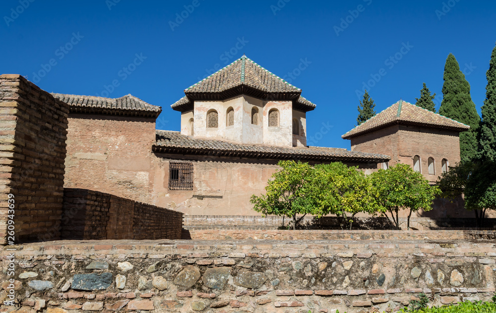 Beautiful views of the gardens and ancient buildings of the Alhambra, against mountains and bright blue sky, Granada, Andalusia, Spain. 