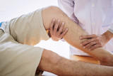 Doctor physiotherapist assisting a male patient while giving exercising treatment massaging the leg of patient in a physio room, rehabilitation physiotherapy concept